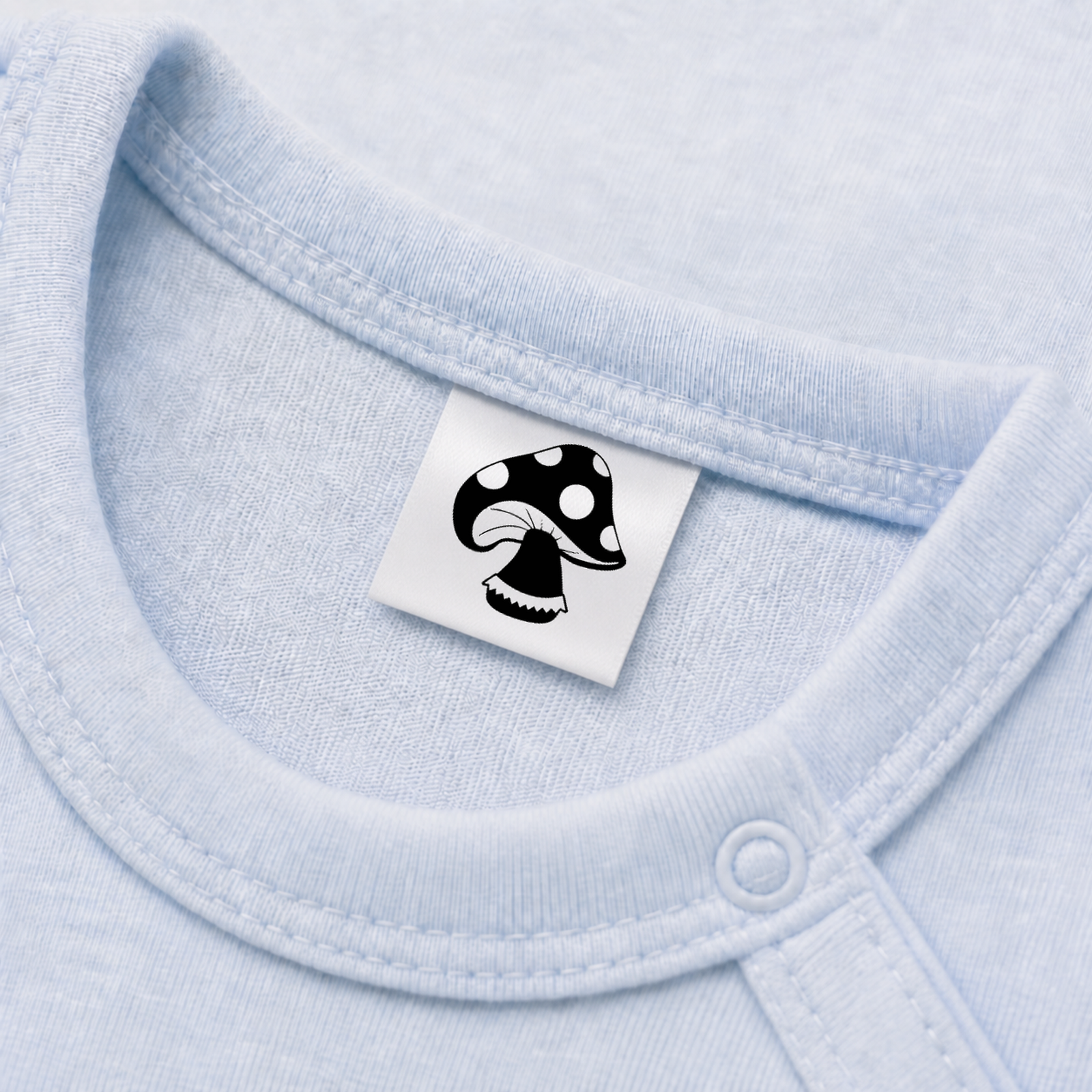 Textiletiketten für Größenbeschriftung mit Pilz Motiv und Größenfeld 5 Eingenähtes Polyester-Satinetikett mit Motiv Fliegenpilz in einem hellblauen Babybody