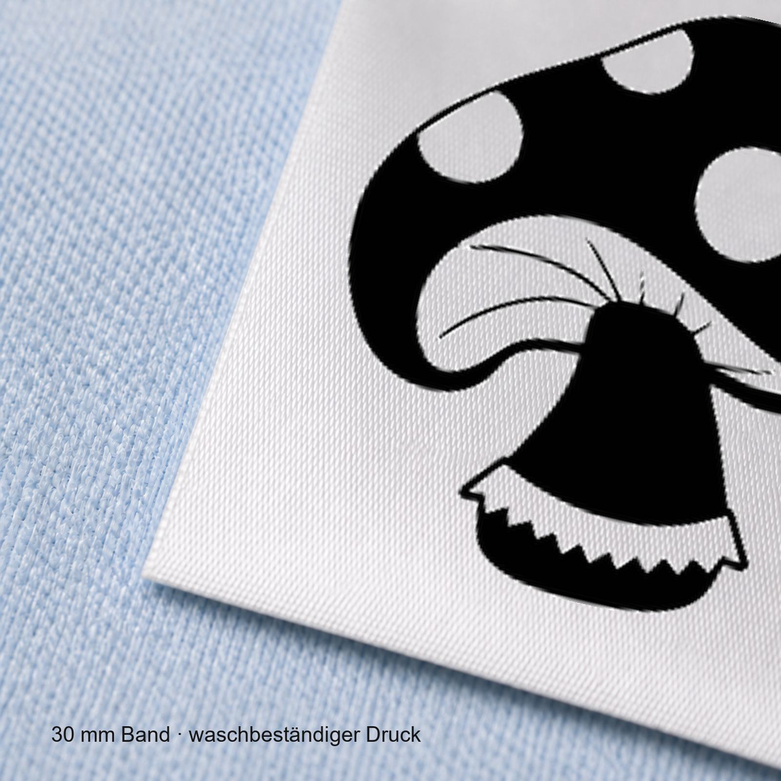 Textiletiketten für Größenbeschriftung mit Pilz Motiv und Größenfeld 6 Nahaufnahme eines bedruckten 30-mm-Polyester-Satinbands mit Motiv Fliegenpilz
