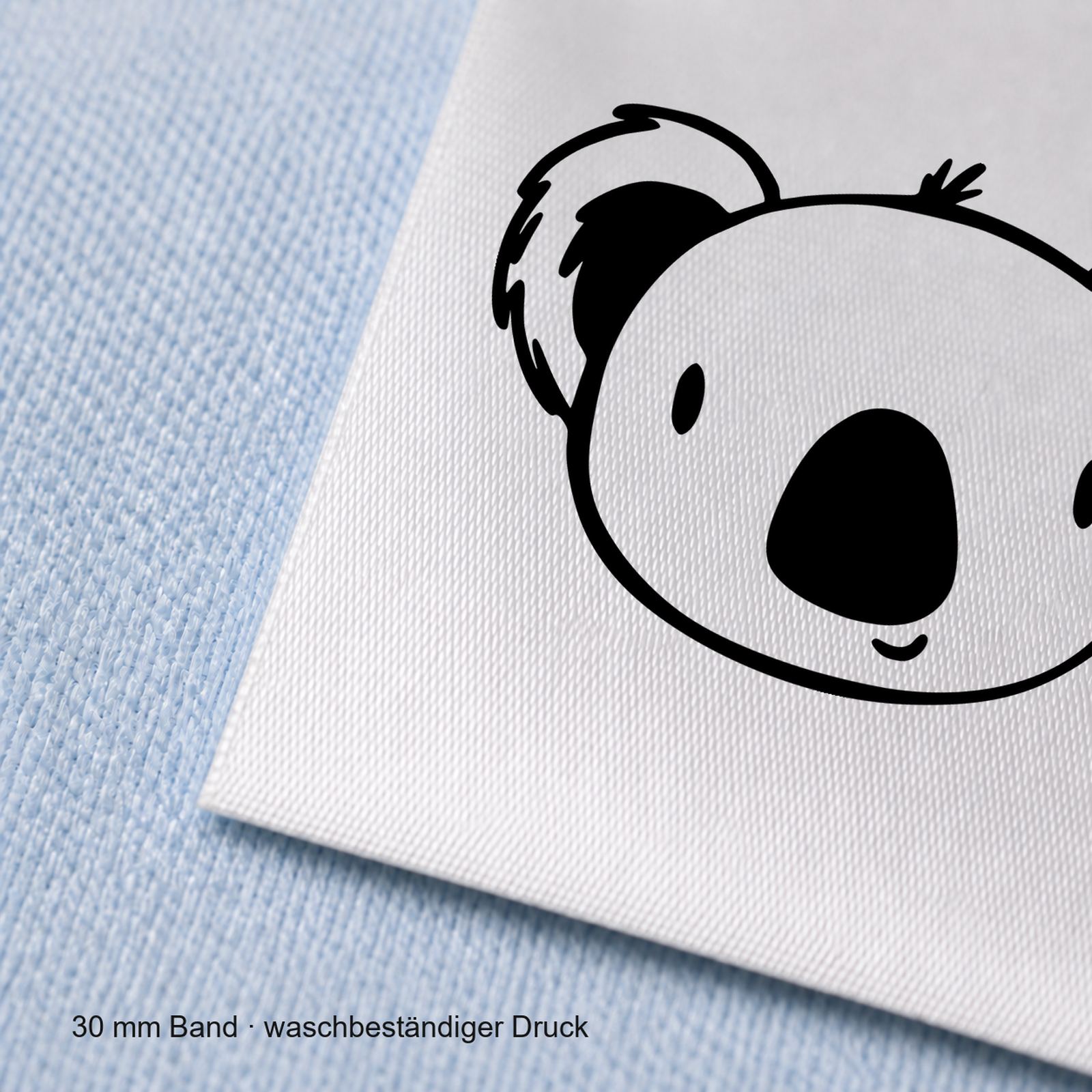 Textiletiketten mit Koala Bär Motiv zur Größenbeschriftung, Motiv von Näherei-Löwenjunges 6 Nahaufnahme eines bedruckten 30-mm-Polyester-Satinbands mit Motiv Koala Bär