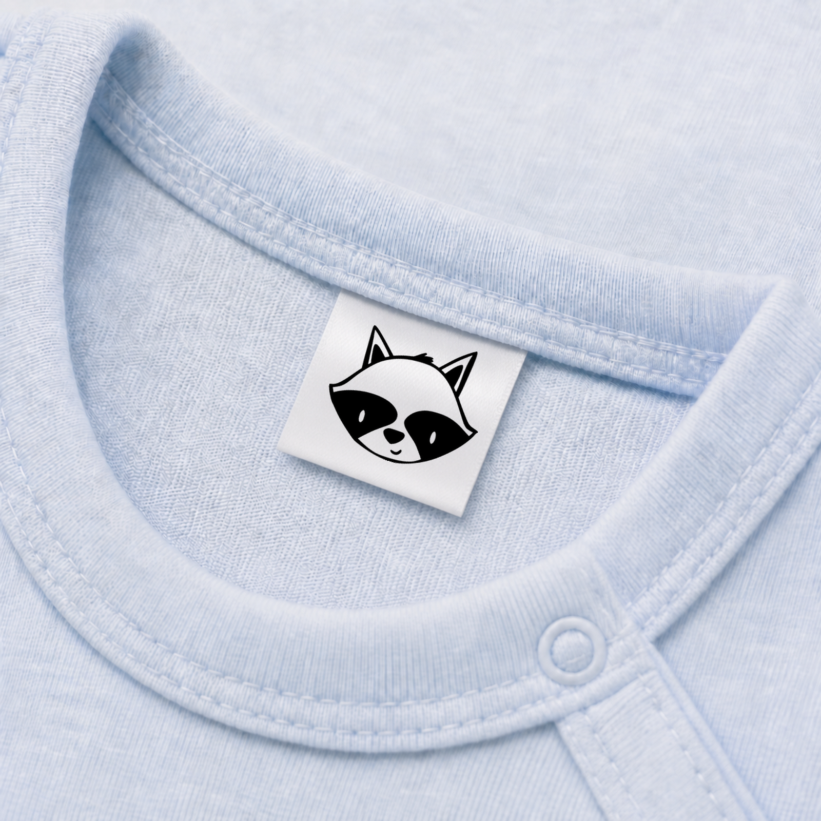 Textiletiketten mit Waschbär Motiv zur Größenbeschriftung, Motiv von Näherei-Löwenjunges 5 Eingenähtes Polyester-Satinetikett mit Motiv Waschbär in einem hellblauen Babybody